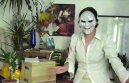 A person stands in a living room wearing a Billy the puppet mask.