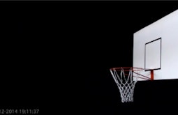 A white basketball back-board floats amongst a black background.