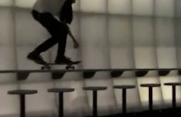 A person skateboards along a bar.