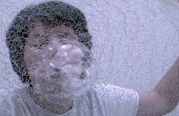 A person blows bubbles through a net.