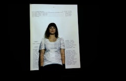 A person stands in front of a projected image of a page from a book.