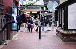 A person hangs off a plant cage in a pedestrian thoroughfare.