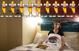 A tired eyed woman sits slumped in a bed staring into the distance. A row of dancing bananas with faces is super imposed along the top of the frame.