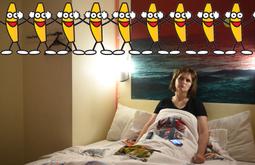 A tired eyed woman sits slumped in a bed staring into the distance. A row of dancing bananas with faces is super imposed along the top of the frame.