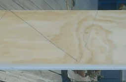 A piece of ply wood with pencil marks for cutting fills the frame.