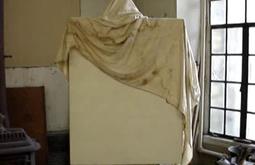 In Thomas Hart Bentons studio a blank canvas is half covered by a cloth.