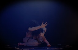A person contorts their body while dancing, they have a ring of beads around them on the ground.