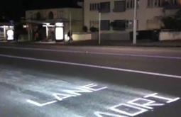 On a suburban street the words Maori Lane have been painted onto the road in the style of road markings.