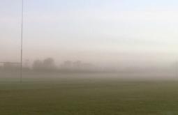 On a rugby field a figure runs through thick fog as the sun rises.