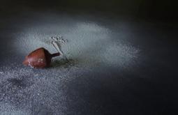 A spinning top spins while flour is sprinkled from above.