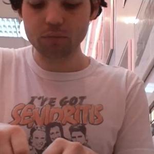 Campbell sits in a booth at Burger King wearing a T-shirt that reads “I’ve got senioritis”. Behind him, the Burger King decor is black and white checkered tiles and framed photographs.