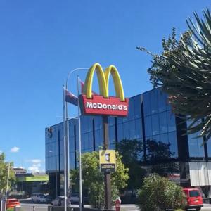 On a bright day in a city McDonald's signage of illuminated golden arches guides customers to the drive-thru