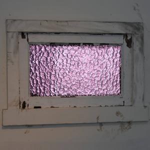 A purple textured glass window with white window frames