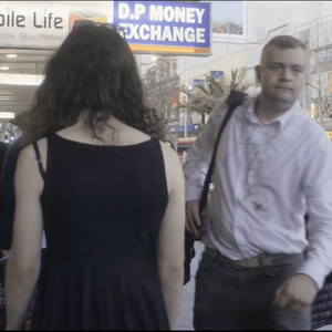 A woman walks along a busy street as city workers walk by