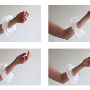 A heavy thick bracelet made of ice is worn on someones arm as they gently clasp and unclasp a fist