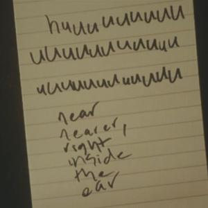 scrawled text on a notepad which begins with three lines spelling 'huuuuu...' and ends with 'near, nearer, right inside the ear'.