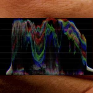 Over a close up image of fingers we see a colourful spectral wave form.