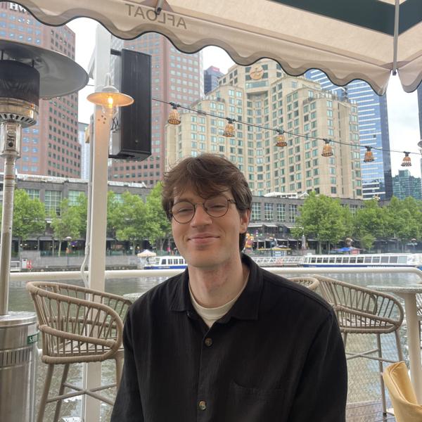 A person sits smiling in a bar, beside a canal