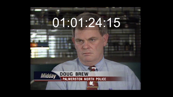A disgruntled police offer in an interview. A video timecode shows over the top of the image, indicating this is raw footage.