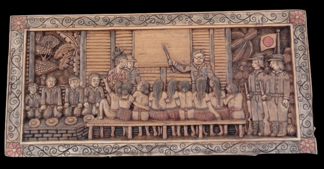 Woodblock carving showing military people teaching indigenous children, holding guns