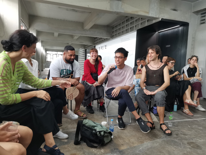 An artist talk, one artist holds the microphone, looks at the moderator and both are laughing.