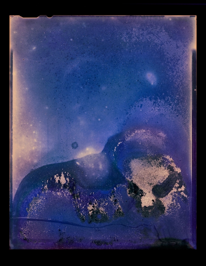 An abstract photo made by submersing the negative in water, which leaves blue and ochre blotchy forms