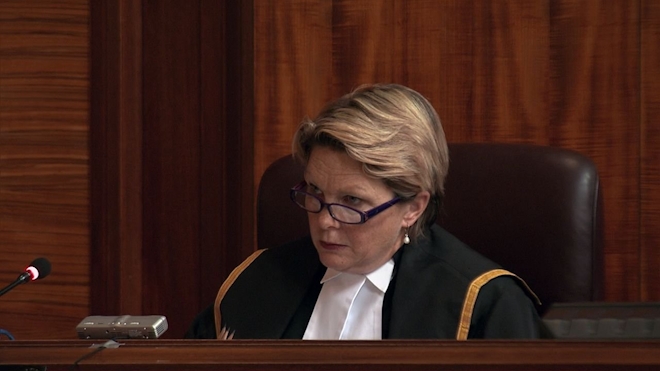 A female judge sits at the bench in a courtroom.
