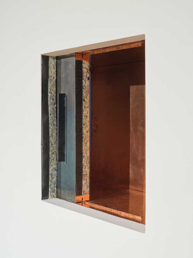 A box inset into a wall with a sliding door. The interior of the box glows an irridescent copper.