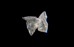 An empty silver wine bladder contracts into a star-like shape as if the air has been sucked out of it. The background is black, which makes the wine bladder appear to float in space.