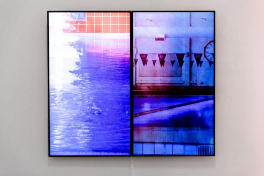 A view of a video art work in a gallery showing a swimming pool